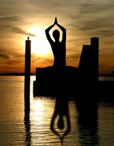 Silhouette of a person meditating near water